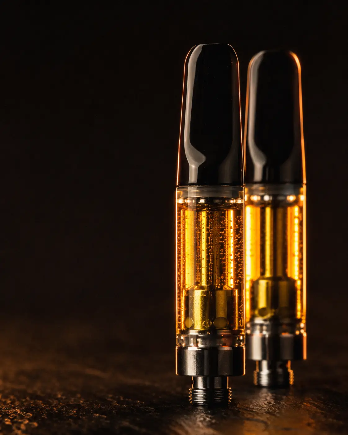 Two glass vape cartridges filled with golden cannabis oil